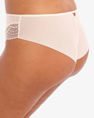 Sidovyu av Elomi Priya Brazilian Trosa i krämvit, där den fräcka ryggtäckningen, den utskurna detaljen bak i midjan och de eleganta volangerna är i fokus.