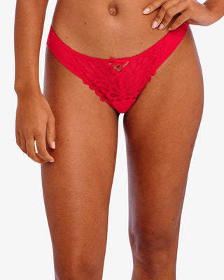 Närbild framifrån på modell som bär röd brasiliansk trosa i transparent broderad mesh med nyckelhålsdetalj och rosett.
