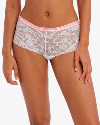 Vit spets-boxertrosa med blommigt mönster, rosa kontrastresår och liten dekorativ rosett framtill, visas på modell med medium hudton framifrån 