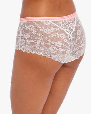 Vit spets-boxertrosa med blommigt mönster, rosa kontrastresår och liten dekorativ rosett framtill, visas på modell med medium hudton snett bakifrån 