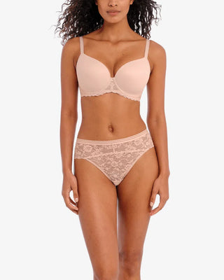 Modell iklädd matchande set från Freya i ljusbeige. Bh:n har släta kupor med spetskant och trosan är i helspets med mjuk resår och medelhög midja.

