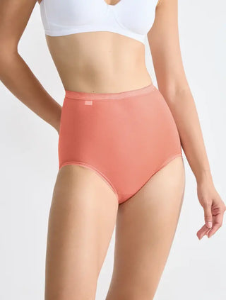 Modell bär Sloggi 3-pack Basic+ maxitrosor i vit, röd och rosa, sedd framifrån