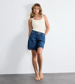 “Modell bär Sloggi Zero Feel Body i vitt med jeans shorts  – vit body utan sömmar eller byglar, med osynlig passform och total rörelsefrihet.” 