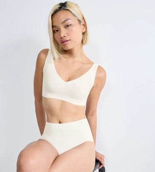 “Halvbild framifrån av Sloggi Zero Feel vit bralette sittandes på en stol – V-ringad bh utan sömmar med avtagbara vadderingar och följsam stretch.”