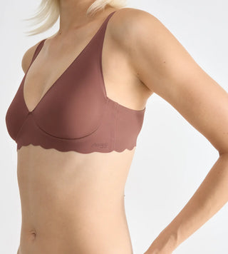 “Närbild på tyg och laserskuren detalj i cacao Sloggi Soft Bra – supermjuk GRS-certifierad mikrofiber med scalloped kant och osynlig finish.”