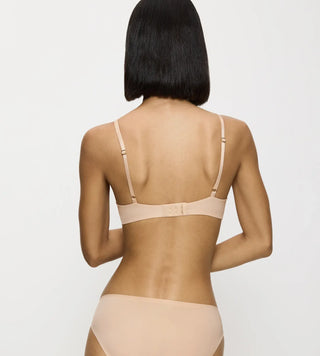Modell sedd bakifrån med Triumph Body Make-Up Essentials Bygel-BH i nude beige – visar ryggparti och knäppning.