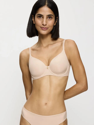 Modell bär nude beige Triumph bygel-bh – lätt vadderad t-shirt-bh med rundad passform och naturligt stöd för vardagsbruk.