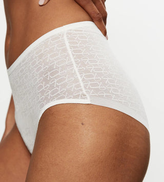 Närbild från sidan på vit Signature Lace maxitrosa, fokus på spetsdetaljer och sömlös passform vid höften.