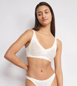 Modell bär vit sloggi ZERO Feel Bliss Soft Bra framifrån – visar fast stöd, grafisk spets och naturlig siluett