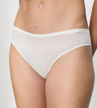 Närbild på vit Signature Lace tai-trosa, fokuserar på spetsens struktur och det eleganta midjebandet.